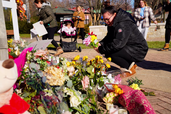 Alexandera Cimbalnik lays flowers at a memorial at Veterans Park after a car plowed through a holiday parade in Waukesha, Wis., on Nov. 23, 2021.