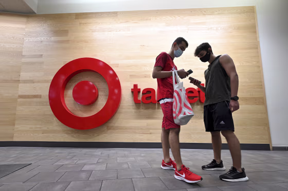 Two men look at their smart phones as they stand outside a Target retail store in Queens, N.Y., on Aug. 12, 2021.