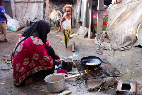 Image: A woman cooks at a makeshift camp for internally displaced people (IDPs) in Aden