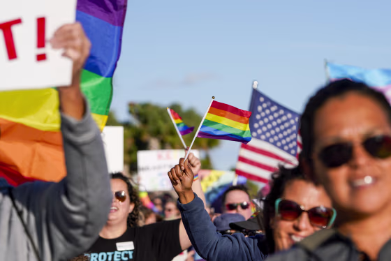 Marchers wave flags and signs as they walk at the St. Pete Pier in St. Petersburg, Fla., on March 12, 2022, to protest the controversial "Don't say gay" bill passed by Florida's Republican-led legislature.