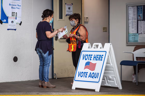 A poll worker speaks with a voter at the entrance to a polling station on Election Day on Nov. 2, 2021 in Miami Beach, Fla.