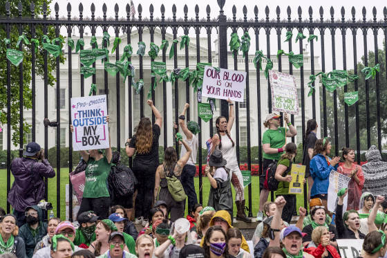 Abortion-rights protesters shout slogans after tying green flags to the fence of the White House during a protest to pressure on the Biden administration to protect abortion rights on July 9, 2022.