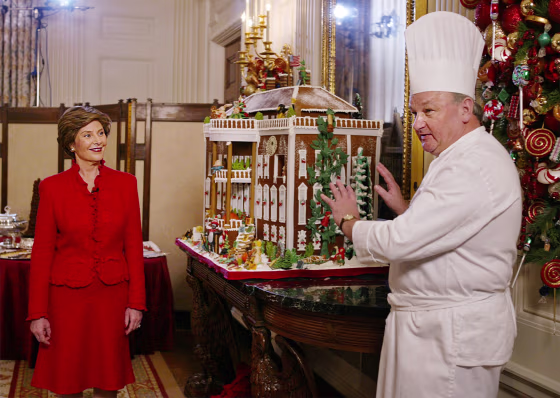 First lady Laura Bush listens to White House pastry chef Roland Mesnier, right, explain the components of the gingerbread White House in December 2003.