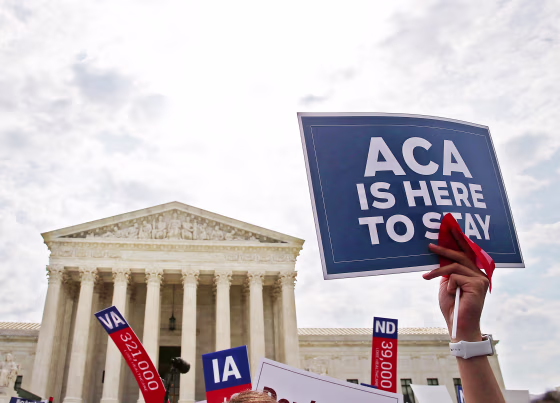 A person holds at sign that reads "ACA Is Here To Stay" at the Supreme Court