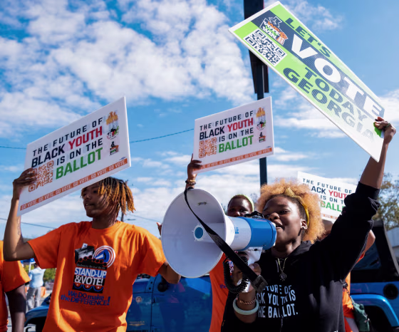 People rally to encourage voter turnout across from a polling location