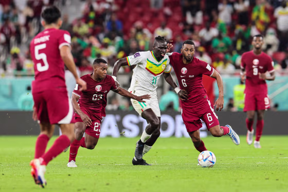 Image: Senegal's midfielder #11 Pathe Ciss fights for the ball with Qatar's midfielder #23 Assim Madibo and Qatar's midfielder #06 Hatim Abdelaziz during the Qatar 2022 World Cup Group A football match between Qatar and Senegal at the Al-Thumama Stadium in Doha on Nov. 25, 2022.