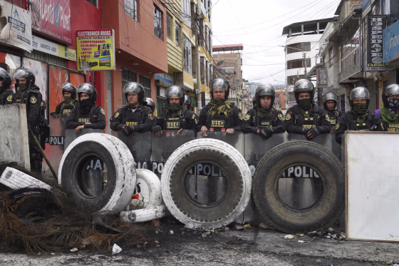 Police stand guard behind a barricade in Andahuaylas, Peru