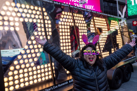Teresa Hui, wearing 2023 glasses, poses in front of the “2023” numerals after the illumination ceremony in Times Square 