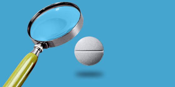 Photo illustration: A magnifying glass hovers over a misoprostol tablet.