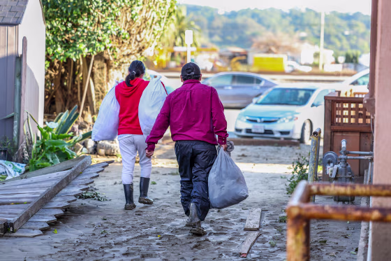 Maria Santiago, left, and her father Alejandro move out with a few belongings after returning home for the first time after the evacuation order was lifted in Pajaro, Calif., on March 23, 2023.