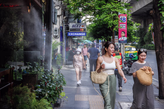 Pedestrians walk past a mist cooling system at a restaurant in Bangkok on April 25, 2023.