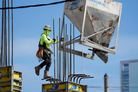 A worker guides a bin into position at a construction site, on Jan. 24, 2023, in Miami.