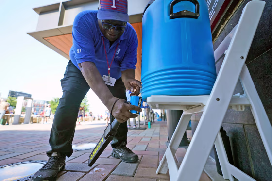 A guard pours water to stay hydrated while working security outside in Arlington, Texas, Monday, June 26, 2023. 