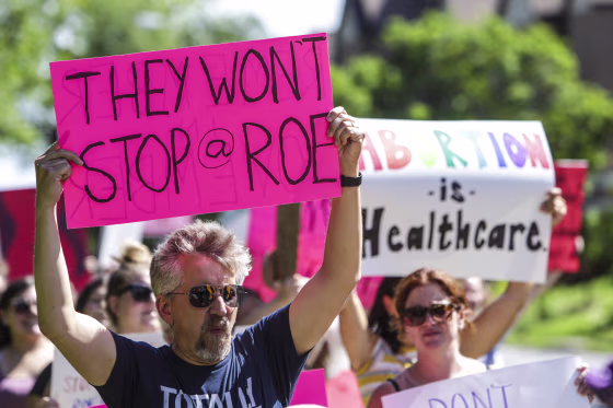 Image: A man holds a sign as community members walk around Vander Veer Park in Davenport, Iowa, during a march following the U.S. Supreme Court decision to overturn Roe v. Wade on June 26, 2022.