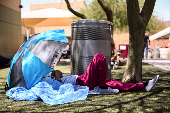 Image: A Phoenix resident rests under shade while seeking protection from the sun and heat at the Human Services Campus during a record heat wave in Phoenix on July 18, 2023.