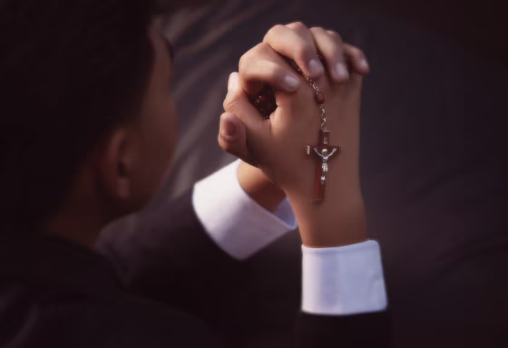 A young boy holding Catholic rosary beads.