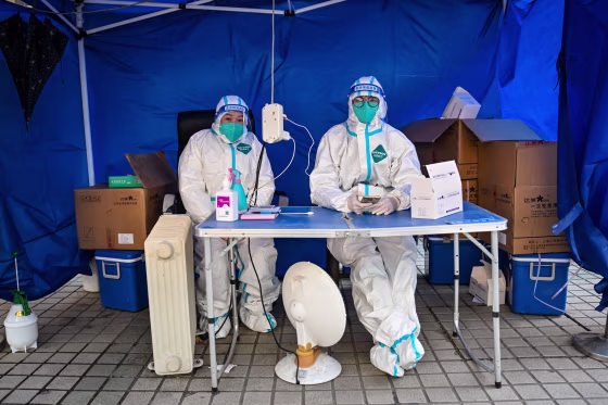 Health workers wait for people to scan a health code to test for the Covid-19 coronavirus in the Jing'an district in Shanghai