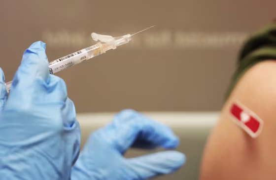 A pharmacist prepares a patient for a COVID vaccine