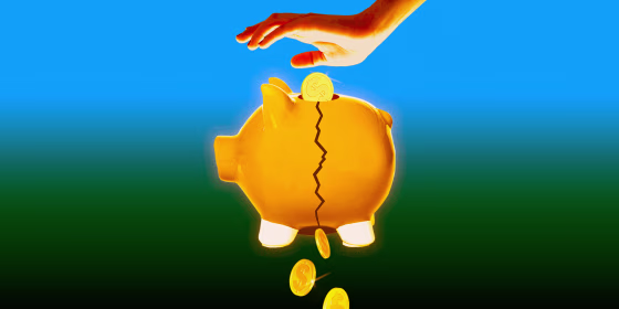Hand dropping coins into piggy bank and coins falling out of the bottom