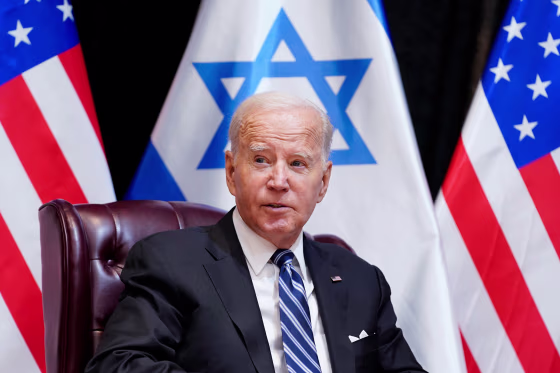 Joe Biden sits in front of Israel and U.S. flags.