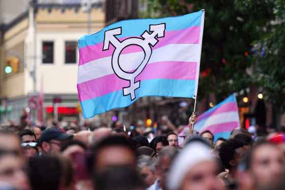 A person holds a transgender pride flag.