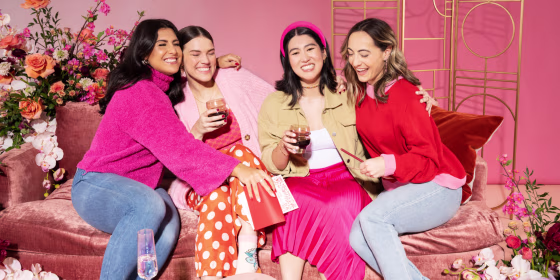 four women embracing while exchanging Galentine's day gifts.