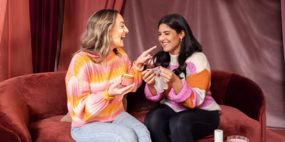 two women who are sisters, laughing while applying skincare products