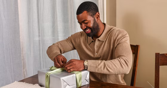 a man opening a gift wrapped in silver paper