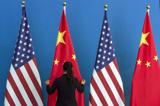 A woman adjusts a flag during the U.S.-China Strategic and Economic Dialogue in Beijing