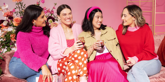 Four women in valentine's day outfits laughing and enjoying each other's company.