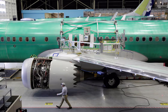 A worker walks past a Boeing 737 MAX-9 under construction at their production facility in Renton, Wash.
