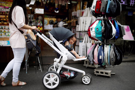 FILE PHOTO: A woman pushing her baby in a stroller shops in the Hongdae area of Seoul