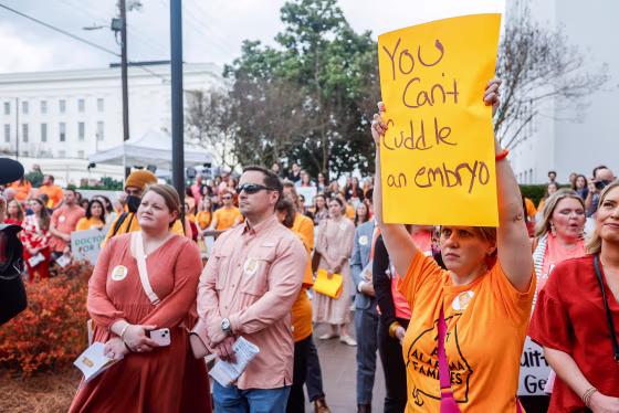 Carrie McNair holds a sign for IVF rights