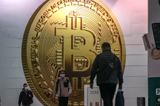 People walk past an ad for Bitcoin in Hong Kong