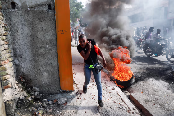 A person runs past burning tires in Haiti