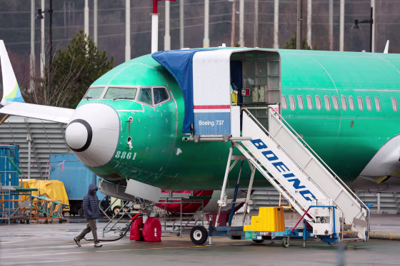 A person walks past an unpainted Boeing 737-8 MAX