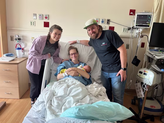 Alex Kamer and her husband, Alan Kamer, in the hospital with their friend Leah Zientek, who was their surrogate and gave birth to their younger son in June.