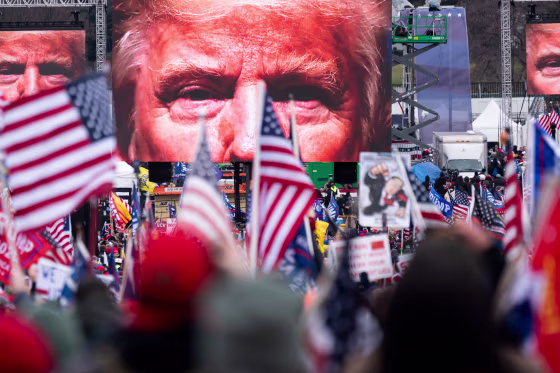 An image of President Donald Trump appears on video screens