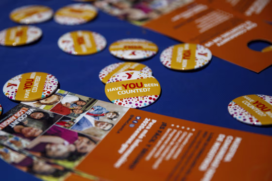 Census 2020 pins and leaflets are displayed on a table during a community food distribution at a YMCA location in Los Angeles