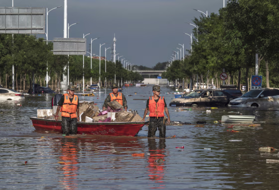 Members of the Peoples Armed Police wade through receding floodwaters as they help to retrieve goods from a building in Zhuozhou, China