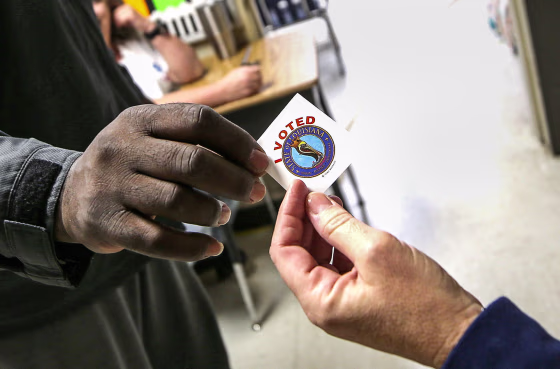 Hand holding an "I Voted" sticker