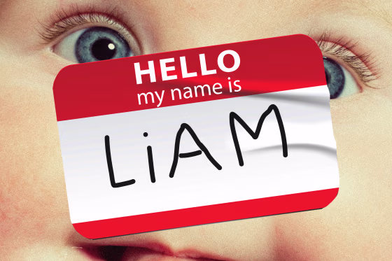 Photo illustration of a close-up of a baby's face; overlaid with a "Hello my name is Liam" sticker