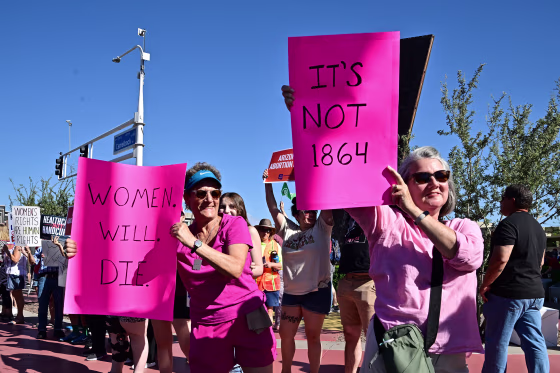 Demonstrators hold signs that read "Women Will Die" and "It's not 1864"