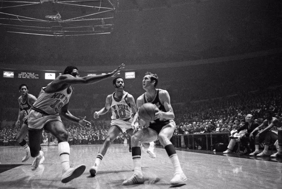 Jerry West of the Los Angeles Lakers crashes against Willis Reed of the New York Knicks as he passes off to Wilt Chamberlain in the opening minutes of the first game of the NBA Championship playoff series in Inglewood, Cal., on May 1, 1973.