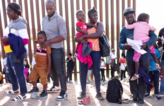 Immigrants from Haiti wait in line to be processed by the U.S. Border Patrol in Yuma, Ariz.