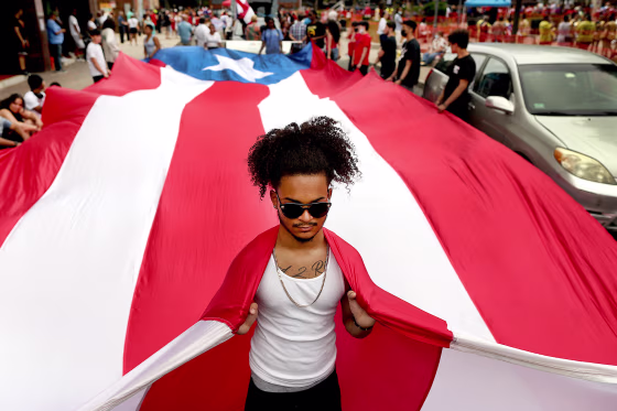 A participant helps carry the flag of Puerto Rico