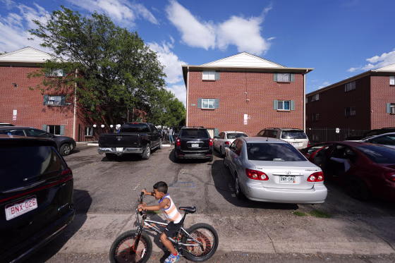 A boy guides his bicycle as a rally is held in the courtyard between apartment buildings in Aurora, Colo., on Sept. 3. Demonstrators said Venezuelans are being unfairly painted as criminals.