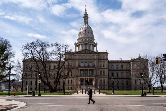A man crosses the street in front of the state capitol building in Lansing, Mich. on April 1, 2024.