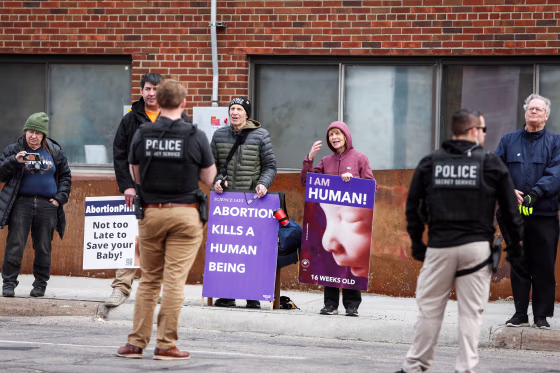 People hold anti-abortion signs outside of a clinic