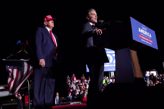 Dr. Mehmet Oz speaks as Donald Trump listens at a rally